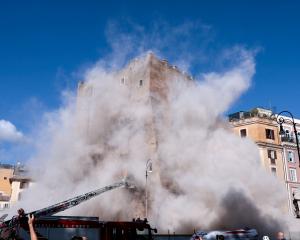 Dust rises as part of the Torre dei Conti tower collapses following an earlier partial collapse,...