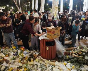 People pay tributes to victims of the fire at the Wang Fuk Court housing complex, in Tai Po, ...