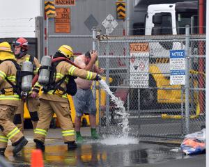 An Interwaste worker is washed down with hoses after getting doused in what is believed to be...