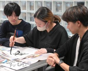 University of Otago Japanese student Maria Miya, 20, does some calligraphy while her peers Naoki...