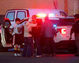People embrace near a police officer outside the Dennis M Lynch Arena, an indoor ice skating rink...
