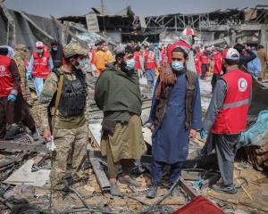 Afghan men stand at the site of a drug rehabilitation hospital destroyed in what the Taliban said...