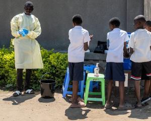 A health worker prepares a hand washing station for students in Bunia as authorities intensify...