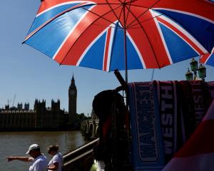 People walk past a souvenir vendor in front of Big Ben in London as the UK experiences record...