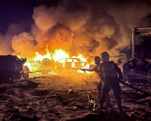 Civil defence workers attempt to extinguish a fire following an Israeli strike on a warehouse in...
