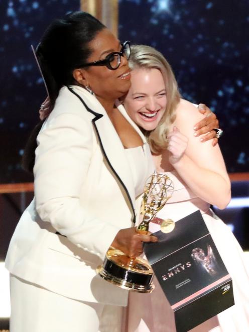 Oprah Winfrey embraces Elizabeth Moss as she presents The Handmaid's Tale with the award for...