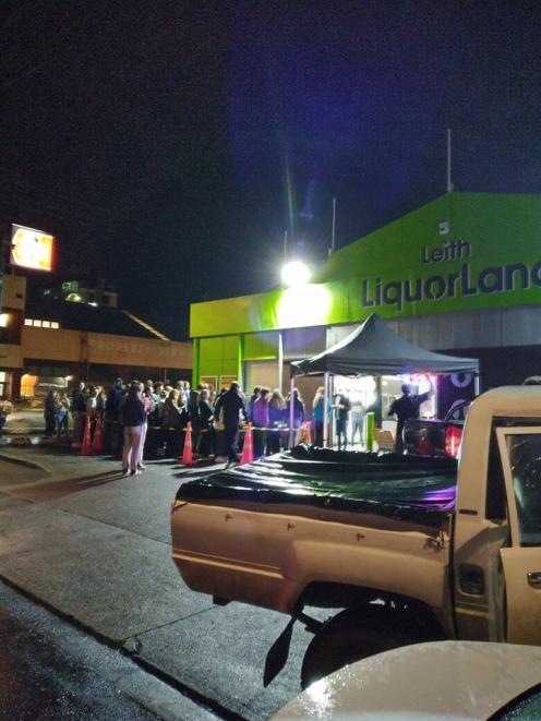 People queue at at liquor store at Leith St last night. Photo: supplied 