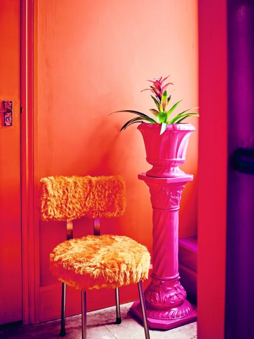 A zesty orange covers the walls and trim in this hallway while the retro chair strikes a fun note...
