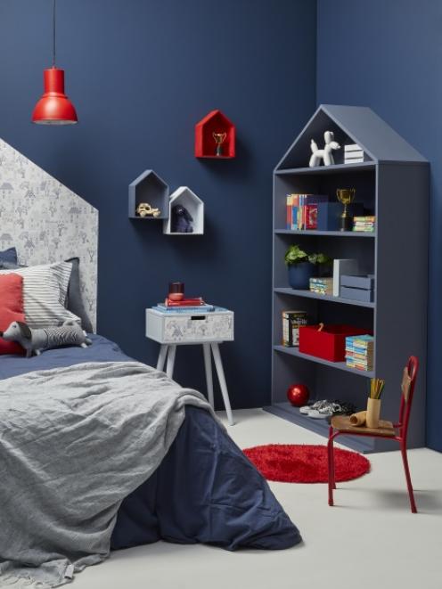 Hot red accents bring a playful approach to this child’s bedroom. House-shaped shelves are in ...