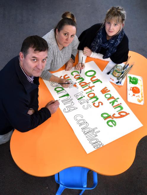 Elmgrove School principal Chris McKinlay and teachers (from left) Carlie Sinclair and Melissa Haggerty paint signs for today's NZEI union strike. Photo: Peter McIntosh