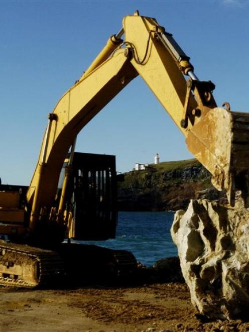 A digger moves a large boulder into place during repair work to the Aramoana mole. Photo by...