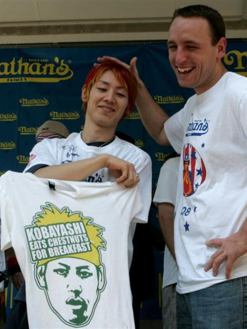 Takeru Kobayashi, left, of Japan poses for photographs with last year's hot dog eating champion...