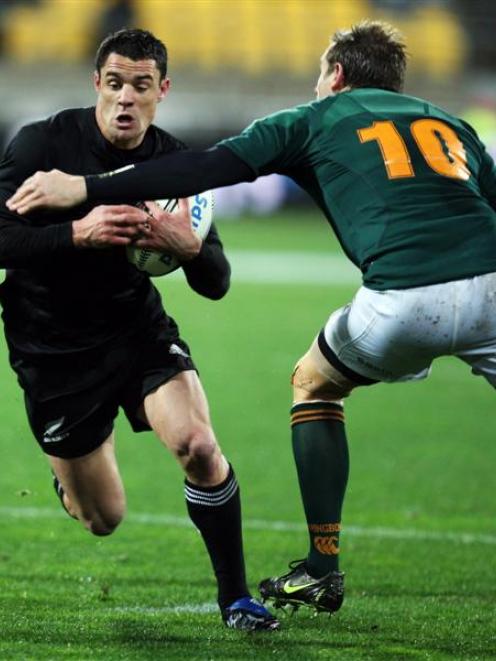All Blacks first five-eighth Dan Carter runs through the tackle of his South African counterpart...