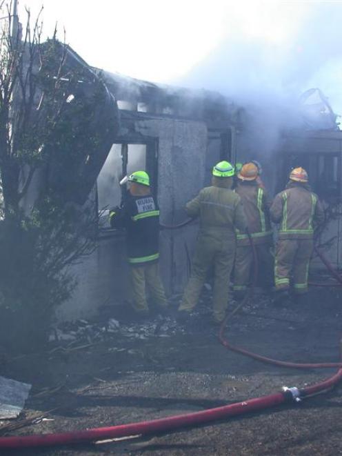 Firefighters dampen down a blaze which destroyed what was a two storey house at Kakanui earlier...