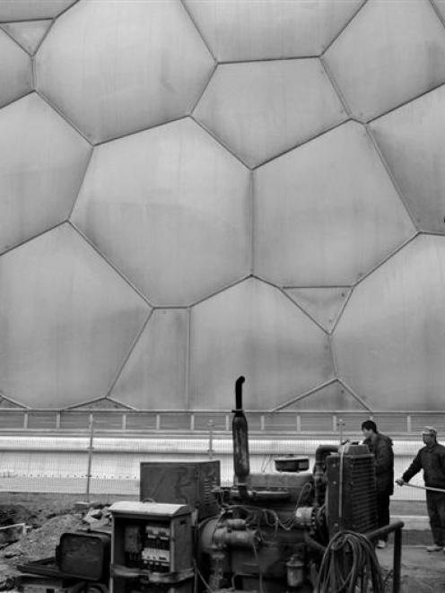 Chinese workers labour near the National Aquatics Center, also known as the Water Cube in Beijing...