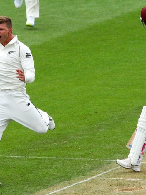 Corey Anderson of New Zealand celebrates after taking the wicket of Darren Bravo of the West...