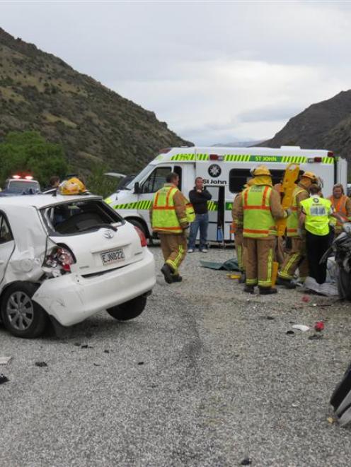 Firefighters and St John ambulance officers attend to one of the drivers involved in a car crash...