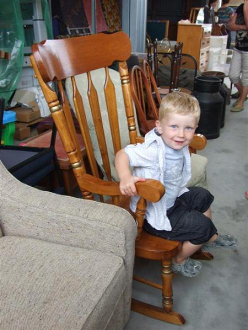 James Gare  (2), of Alexandra, tries out a rocking chair during one of three auctions and garage...