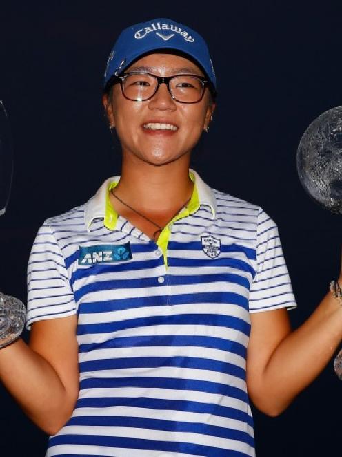 Lydia Ko poses with the CME Tour Championship trophy and the CME Race for the Globe trophy...