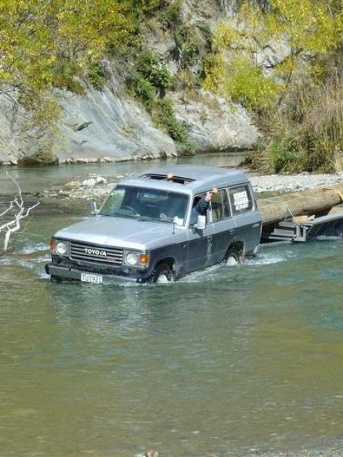 A 4WD completes one of 10 river crossings with two of the logs used to construct a bridge over...