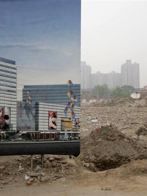 A billboard blocks the view to a construction site against the backdrop of a polluted skyline in...