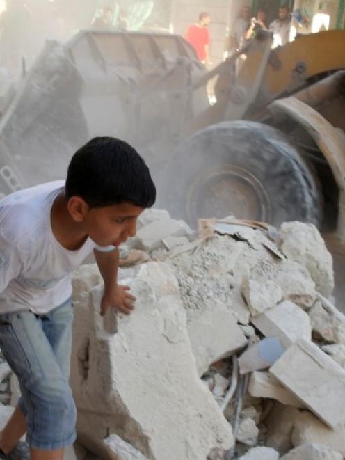 A boy walks beside a bulldozer while people look for survivors following what activists say was...