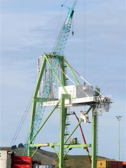 A cab from a Port Otago crane (in the centre of the picture) is lowered to the ground as workers...