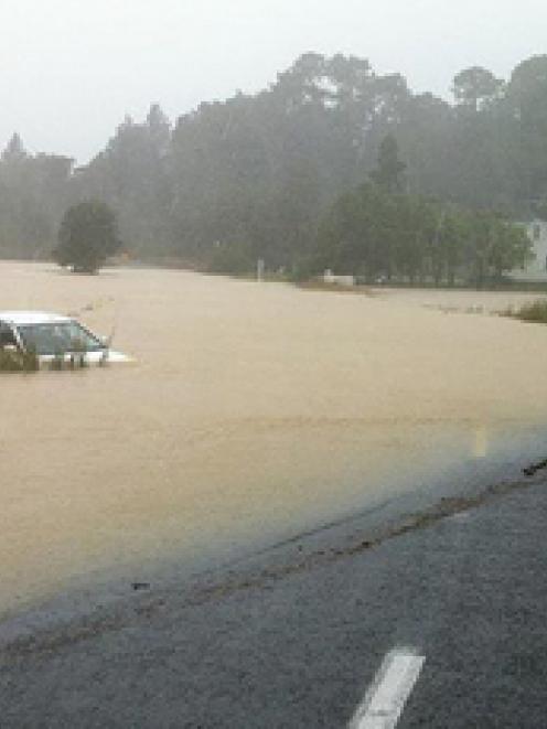 A car is stuck in rising flood waters after heavy rain near Whangarei. Photo / APN