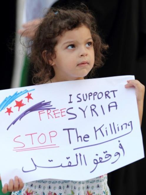 A child holds a banner as she participates in an anti-Syria regime protest held by Bahrainis at...