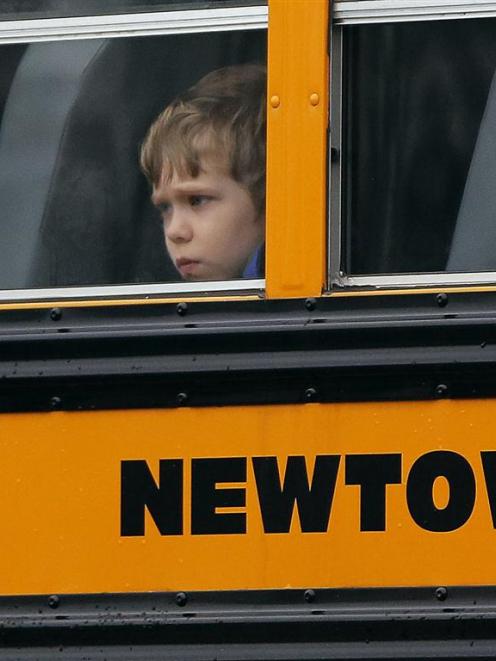 A child looks out of the window of a school bus carrying students from the Newtown school...