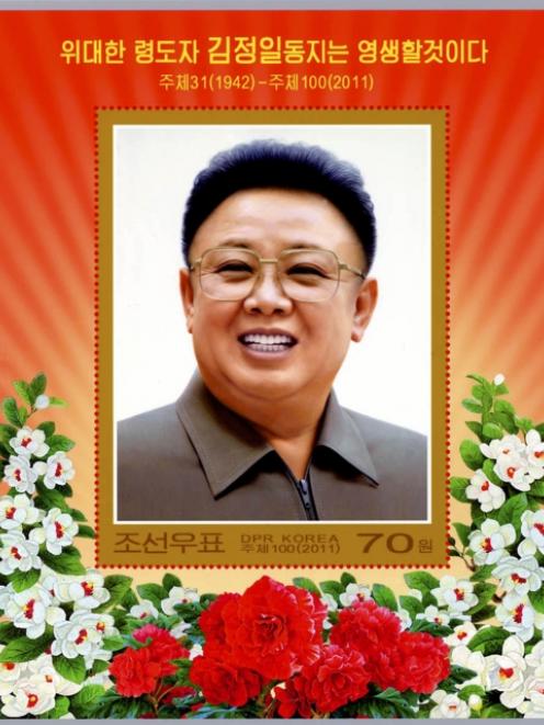 A commemorative stamp featuring late North Korean leader Kim Jong-il. The Korean characters read ...