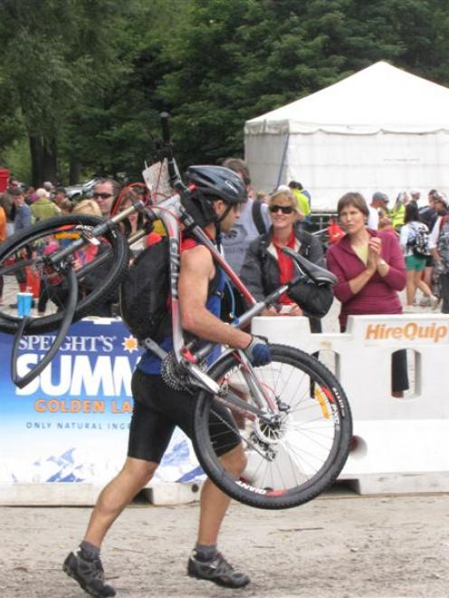 A competitor in the 2012 Motatapu mountain bike event is forced to carry his bike as he nears the...