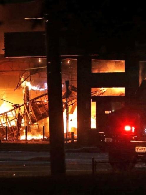 A convenience store burns during a night of rioting in Ferguson, Missouri after the death of...