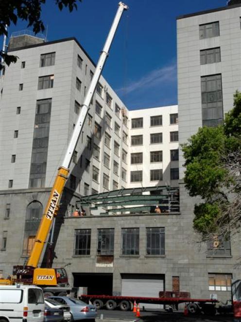 A crane lifts another steel beam into position at the rear of Dunedin's former chief post office...