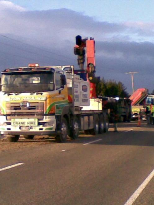 A crane truck is used to assist after a truck and trailer rolled off the road on SH1 near Hampden...