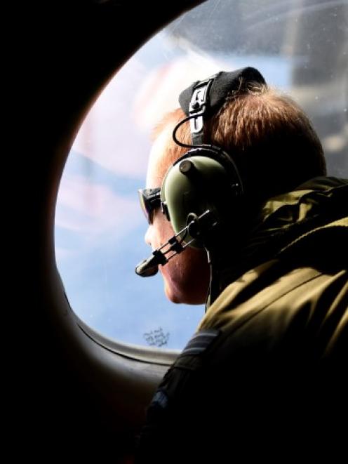 A crew member looks out an observation window aboard a Royal New Zealand Air Force P3 Orion...