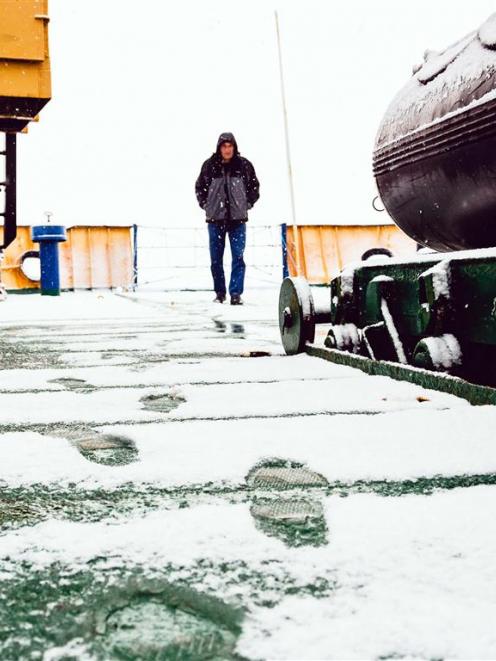 A crew member of the Akademik Shokalskiy walks on the snow-covered aft deck of the stranded ship...