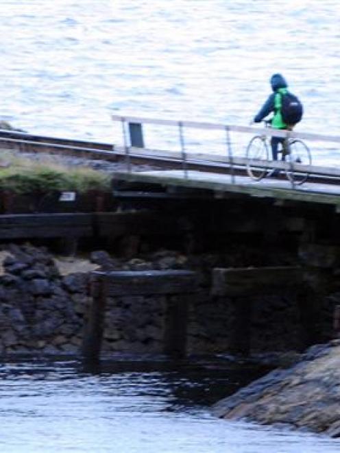 A cyclist crosses a narrow railway bridge at the Burkes inlet, between Dunedin and Port Chalmers....