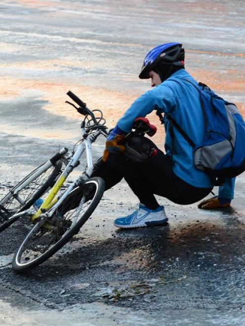 A cyclist picks himself up after slipping on ice on Regent Rd yesterday morning. Photo by ODT.