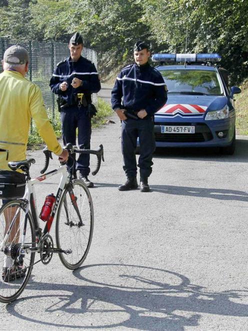 A cyclist speaks to French gendarmes as they block access to a road to La Combe d'Ire in...