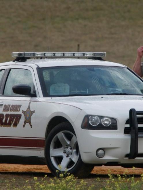 A Dale County Sheriff's deputy stands at a roadblock near the scene of a shooting and the...