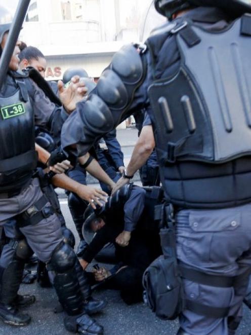 A demonstrator (C, rear) is detained by riot police before the 2014 World Cup final between...
