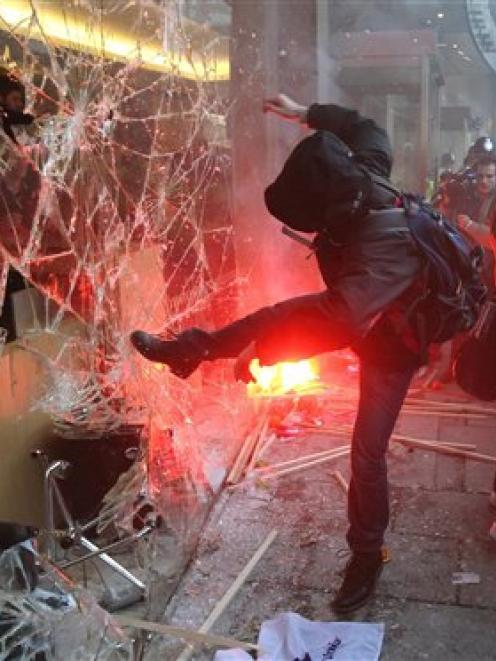 A demonstrator kicks the windows of Millbank Tower, housing the headquarters of the Conservative...