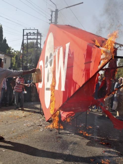 A demonstrator throws kerosene oil on an effigy depicting Dow Chemical Company, which now owns...