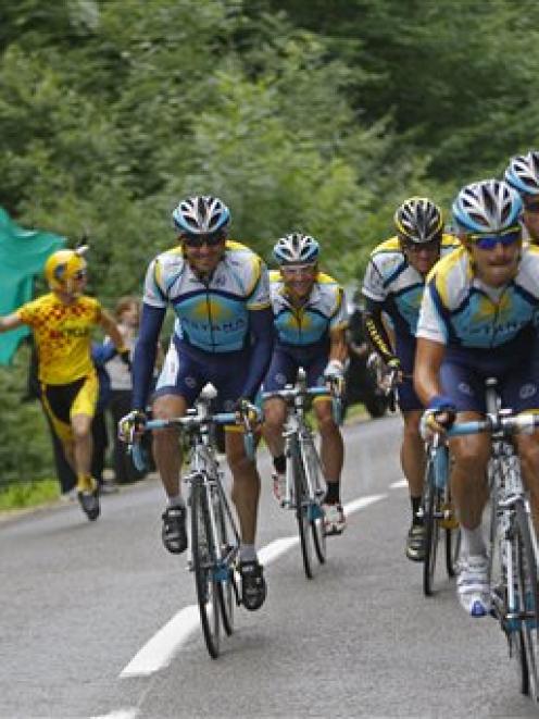 A fan with an American flag runs alongside the pack led by the Astana team with American seven...