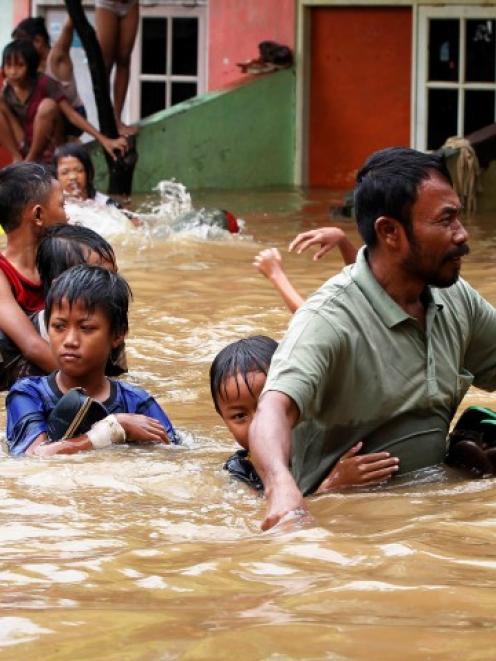 A father escorts his son as they evacuate a flooded area in Jakarta. REUTERS/Enny Nuraheni