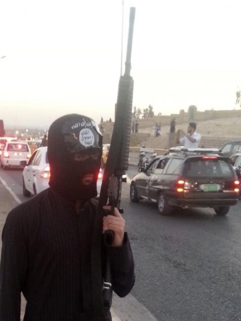 A fighter of the Islamic State of Iraq and the Levant (ISIL) stands guard with his weapon by the...