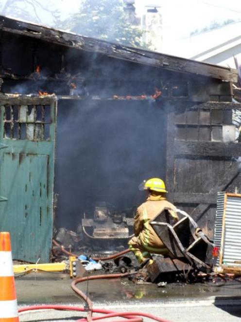 A fireman works at the scene of a shed fire in Exe St yesterday. Photo by Sally Rae.
