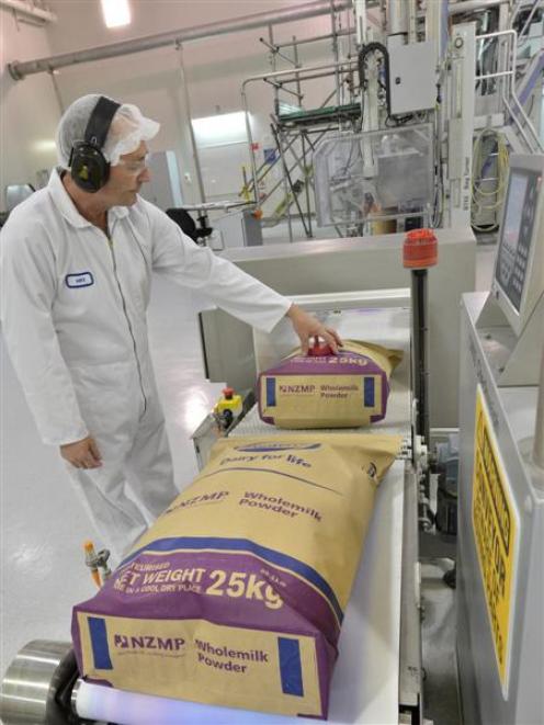 A Fonterra Studholme plant worker watches bags of  milk powder roll off the line. Photo by Fonterra.