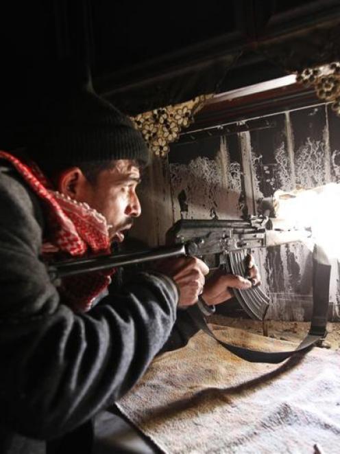 A Free Syrian Army fighter takes up position inside a burnt room in the Aleppo district of...